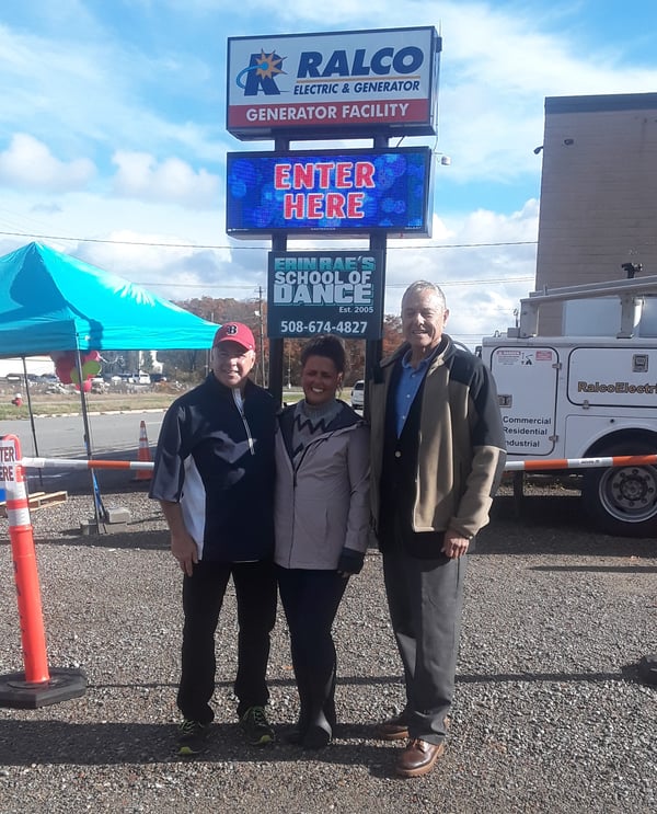 family in front of RALCO sign during food drive